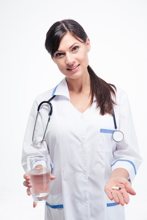 Happy female doctor holding medication and glass of water isolated on a white background. Looking at cameraの写真素材