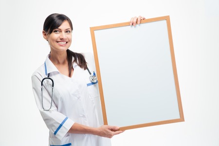 Smiling medical doctor holding blank board isolated on a white background. Looking at cameraの写真素材