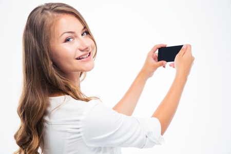 Happy woman making photo on smarptone and looking back at camera
