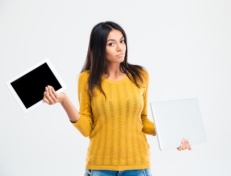 Happy young woman holding tablet computer and laptop isolated on a white backgroundの写真素材