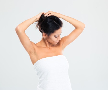Happy young woman in towel making hairstyle isolated on a white backgroundの写真素材