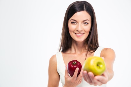 Smiling young woman giving apple on camera isolated on a white backgroundの写真素材