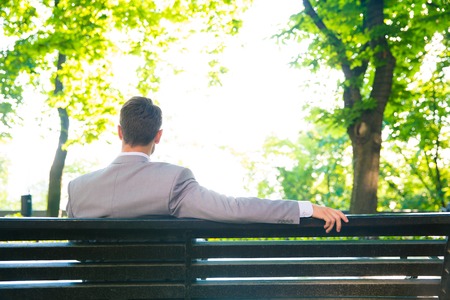 Back view portrait of a businessman sitting on the bench outdoorsの写真素材