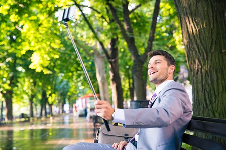 Cheerful businessman making selfie photo on smartphone outdoorsの写真素材