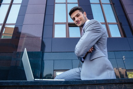 Portrait of a happy businessman with laptop outdoors. Looking at cameraの写真素材
