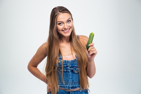 Portrait of a smiling girl holding cucumber isolated on a white background. Looking at cameraの写真素材