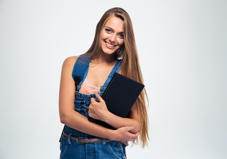 Portrait of a smiling young girl holding book isolated on a white background. Looking at cameraの写真素材