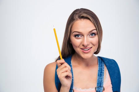 Portrait of a smiling young student holding pencil isolated on a white background and looking at cameraの写真素材
