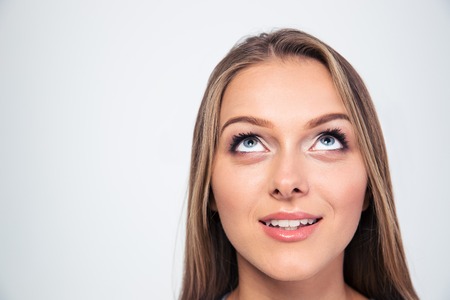 Closeup portrait of a smiling young woman looking up isolated on a white backgroundの写真素材