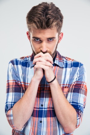 Portrait of a young man praying isolated on a white background. Looking at cameraの写真素材