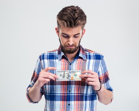 Portrait of a young man holding bill of USA dollar isolated on a white backgroundの写真素材