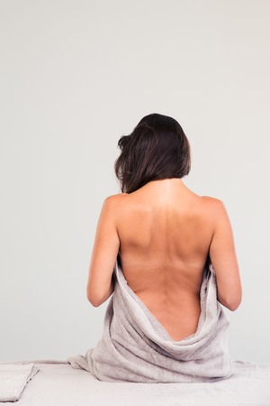 Back view portrait of a woman sitting on massage lounger in a wellness centerの写真素材