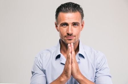 Portrait of a confident businessman praying isolated on a white backgroundの写真素材