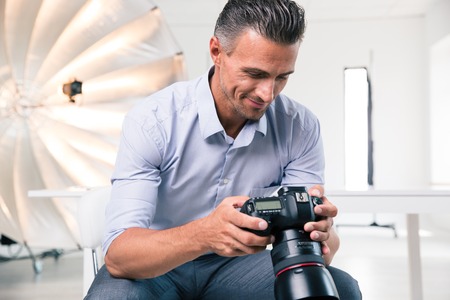 Portrait of a happy photographer using camera in studioの写真素材