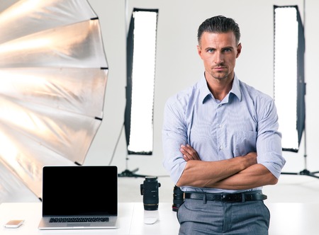Portrait of a confident businessman standing with arms folded in studioの写真素材