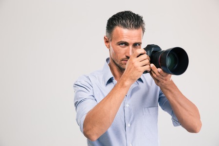 Handsome young man holding camera isolated on a white backgroundの写真素材