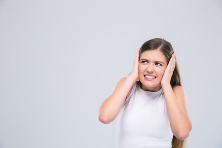 Portrait of a female teenager covering her ears isolated on a white backgroundの写真素材