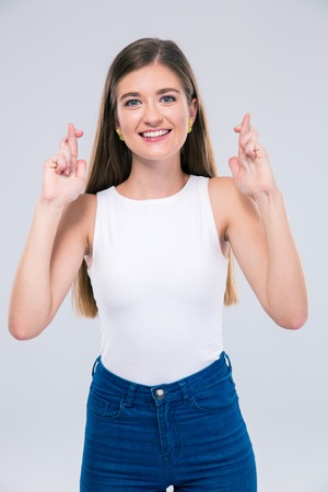 Portrait of a smiling female teenager showing gesture with crossed fingers isolated on a white backgroundの写真素材