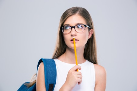 Portrait of a pensive female teenager holding pencil isolated on a white background. Looking awayの写真素材