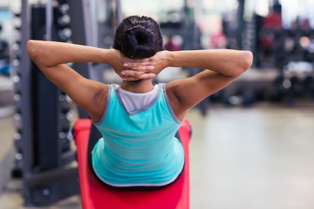 Back view portrait of a fitness woman workout on exercises machine in fitness gym