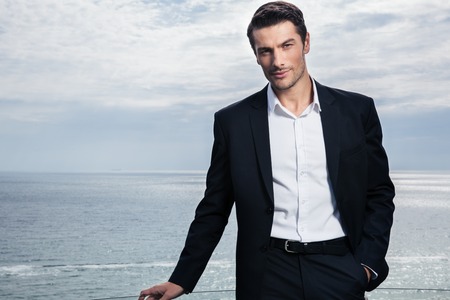 Handsome businessman standing outdoors with sea on backgroundの写真素材