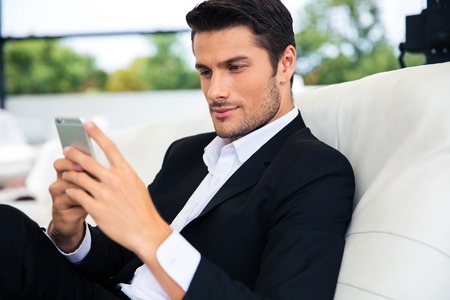 Confident businessman using smartphone in restaurantの写真素材