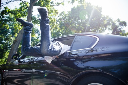 Man jumping in car through window