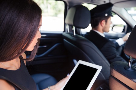 Woman using tablet computer while riding in taxi