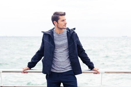 Portrait of a handsome man in sports wear standing outdoors with sea on backgroundの写真素材
