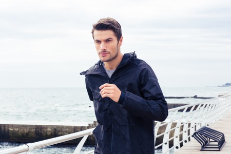 Portrait of a young sports man running outdoors near seaの写真素材