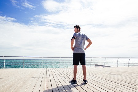 Back view portrait of a sports man standing near sea outdoorsの写真素材