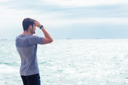 Portrait of a man in sports wear looking at the sea outdoorsの写真素材