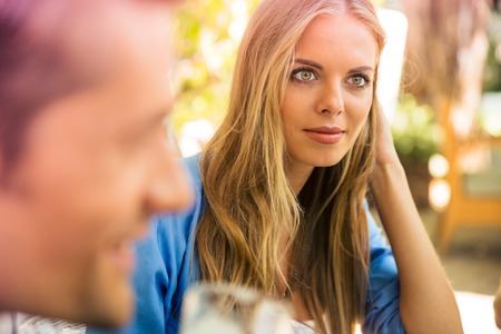 Portrait of a young woman sitting in outdoor restaurant with her friends