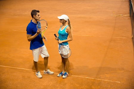 Portrait of a two tennis players with racket talking at courtの写真素材