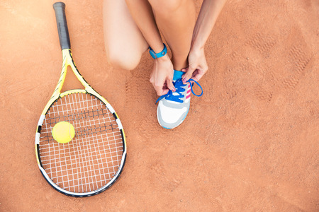 Tennis player tying shoelaces outdoorsの写真素材