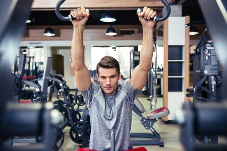 Portrait of a handsome bodybuilder doing exercise on a fitness machine in gym