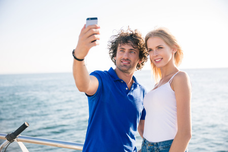 Portrait of a happy couple making selfie photo on smartphone outdoors