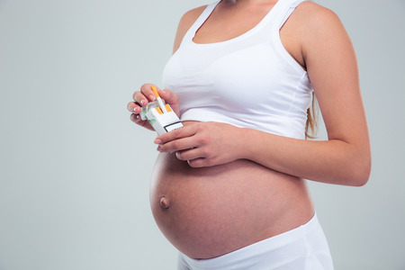 Closeup portrait of a pregnant woman holding cigarettes isolated on a white backgroundの写真素材