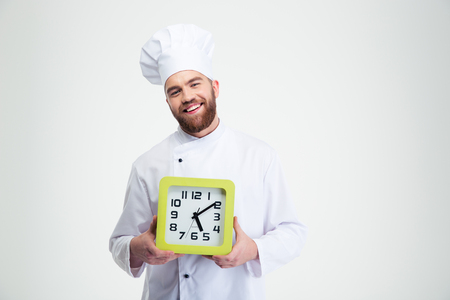 Portrait of a laughing male chef cook holding wall clock isolated on a white backgroundの写真素材