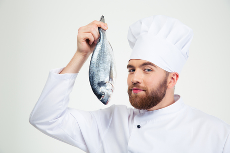Portrait of a handsome male chef cook holding fish isolated on a white backgroundの写真素材