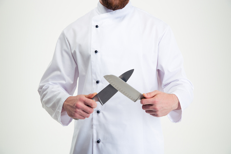 Closeup portrait of a male chef cook sharpening knife isolated on a white backgroundの写真素材