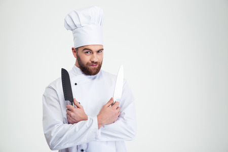 Portrait of a handsome male chef cook holding knifes isolated on a white backgroundの写真素材