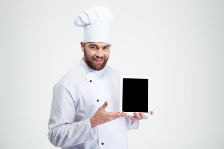Portrait of a happy male chef cook showing blank tablet computer screen isolated on a white backgroundの写真素材