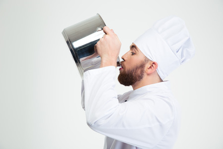 Portrait of a male chef cook drinking from pot isolated on a white backgroundの写真素材