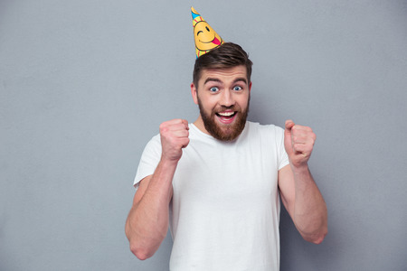 Portrait of a cheerful man with birthday hat standing over gray backgroundの写真素材