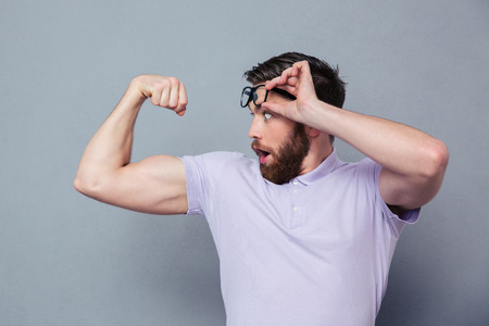 Potrait of a man looking at his biceps with delight over gray backgroundの写真素材