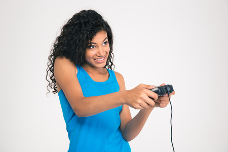 Portrait of a happy afro american woman playing in video game with joystick isolated on a white...