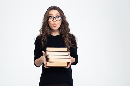 Portrait of amazed woman in glasses holding books and looking at camera isolated on a white background