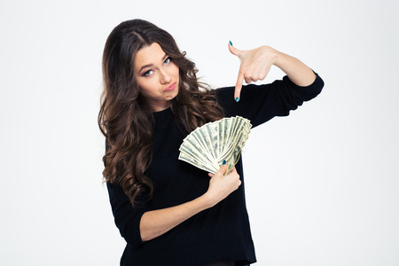 Portrait of a young beautiful girl pointing finger on dollar bills isolated on a white background