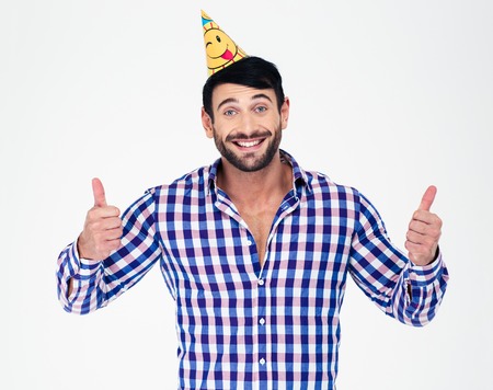 Portrait of a happy man in party hat showing thumbs up isolated on a white backgroundの写真素材